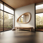 May include: A modern, organic-shaped wooden bench with a light brown cushion sits in a minimalist room with large windows and a unique, oval-shaped wooden mirror on the wall.