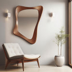 May include: A white armchair with a wooden frame and a curved, wooden, abstract mirror on a white wall. A potted plant with green leaves is in the corner of the room.