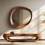 May include: A wooden bench with a curved design and a cushion. The bench is in front of a wall with a large, oval-shaped mirror with a wooden frame.