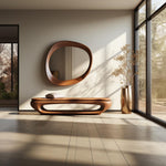 May include: A wooden bench with a curved design and a cushion. The bench is in front of a large, oval-shaped wooden mirror with a natural wood finish. A vase with dried branches is on the right side of the image.