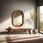 May include: A wooden bench with a unique, organic design, featuring a curved, open-frame base and a wide, flat top. The bench is positioned in front of a large, oval-shaped mirror with a wooden frame, and a potted plant is visible in the background.