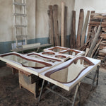 May include: Several wooden frames with a white background and a brown wood border are arranged on a table. The frames are different sizes and shapes, and some have a mirror-like surface.