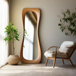 May include: A wooden framed full-length mirror with a curved design, standing in a room with a white armchair and a potted plant.