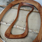 May include: Two wooden frames and a curved wooden handle. The frames are oval-shaped, and the handle has a unique, ergonomic design. The wood has a warm, reddish-brown hue, with visible grain patterns. The items appear to be handmade.