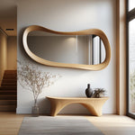 May include: A large, organically shaped wooden mirror hangs above a matching wooden bench. A vase with dried branches and a dark vase with a plant sit on the bench. The room has a neutral color palette with a rug.