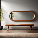 May include: A mid-century modern style interior scene featuring a large, oval-shaped mirror with a wooden frame. Below the mirror is a matching wooden bench with tapered legs. A potted plant is on the left.