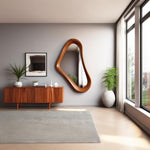 May include: A modern living room featuring a wooden cabinet, a large, uniquely shaped wooden mirror, and a framed abstract artwork. A gray rug and a white vase with a plant are also present.