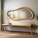 May include: A modern, organic-shaped wooden mirror with a light brown finish hangs above a matching wooden bench. The bench has a curved design and angled legs. Decorative items sit on the bench.