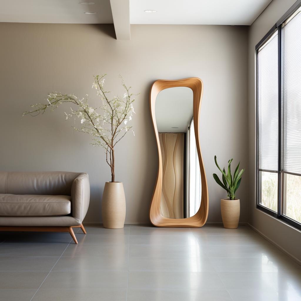 May include: A modern, full-length mirror with a unique, organic wooden frame. The mirror stands tall against a neutral-toned wall, reflecting the room. A beige leather sofa, potted plants, and a window with blinds complete the interior scene.