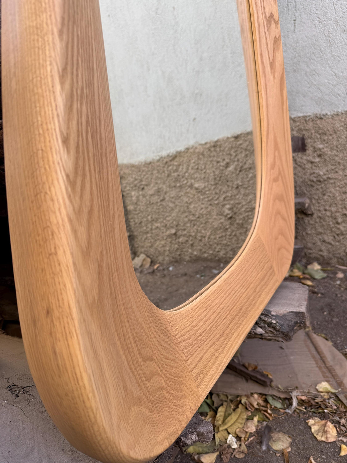 May include: A wall mirror featuring a thick, light-toned natural wood frame with a prominent grain pattern. The frame has rounded corners and a smooth, polished finish, surrounding a reflective glass surface that captures a clear, undistorted view.