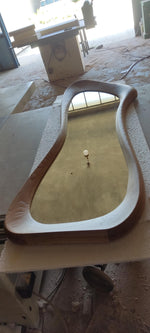 May include: A large, uniquely shaped wooden mirror with a light brown frame. The mirror has a smooth, curved design and is set against a neutral background. The frame appears to be made of solid wood.