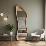 May include: A full-length, free-standing mirror with a unique, organic wooden frame. The mirror reflects a living room scene with a sofa, artwork, and a chair. The room has a neutral color palette with a plant and decorative lighting.