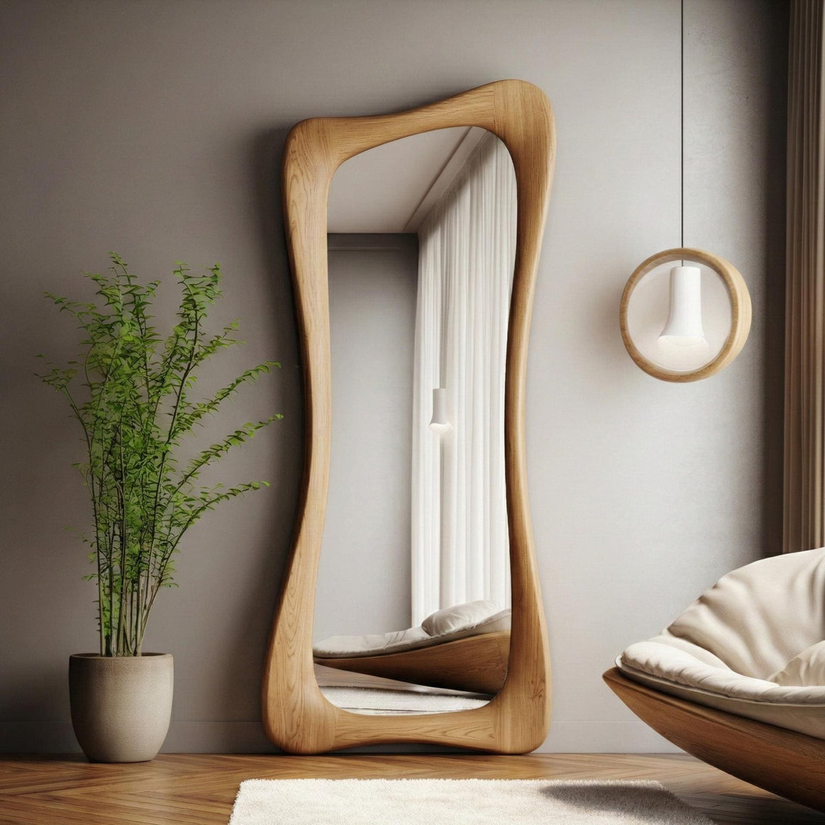 May include: A full-length, free-standing mirror with a unique, organic wooden frame. The mirror's shape is asymmetrical, with gently curving edges. The wood has a natural, light brown finish. The mirror reflects a room with a bed and a window.