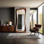 May include: A large, wooden-framed mirror with an organic, flowing shape. The mirror is tall and leans against a neutral-colored wall. The room features a wooden cabinet, a rug, and a leather armchair, creating a modern interior design.