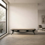May include: A modern bench with a black, openwork base and a tan cushion. The bench is in a room with a large window and a neutral color palette. The design is minimalist and contemporary, suitable for interior decor.