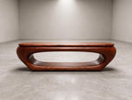 May include: A mid-century modern coffee table with a rich, reddish-brown finish. The table features a unique, oval-shaped design with a hollowed-out center. The table is approximately 48 inches long and 16 inches high.