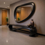 May include: A modern entryway featuring a large, oval-shaped black mirror above a matching black bench. Two bronze vases and a small decorative bowl sit on the bench. The walls are a neutral color, and the floor is tiled.