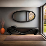 May include: A modern interior featuring a dark wood console table with a unique, curved design, a matching oval mirror, and a decorative orange vase. A brown rug sits on the wooden floor. The room has a neutral color palette.