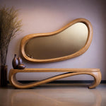 May include: A modern, organic-shaped wooden mirror with a matching bench. The mirror has a light brown, curved frame and a reflective surface. The bench features a unique, flowing design. Decorative brown vases are on the bench.