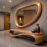 May include: A modern entryway featuring a large, oval-shaped wooden mirror with a matching bench. The bench has a unique, curved design. Two dark brown vases and a small round vase sit on the bench. The walls are a neutral color.