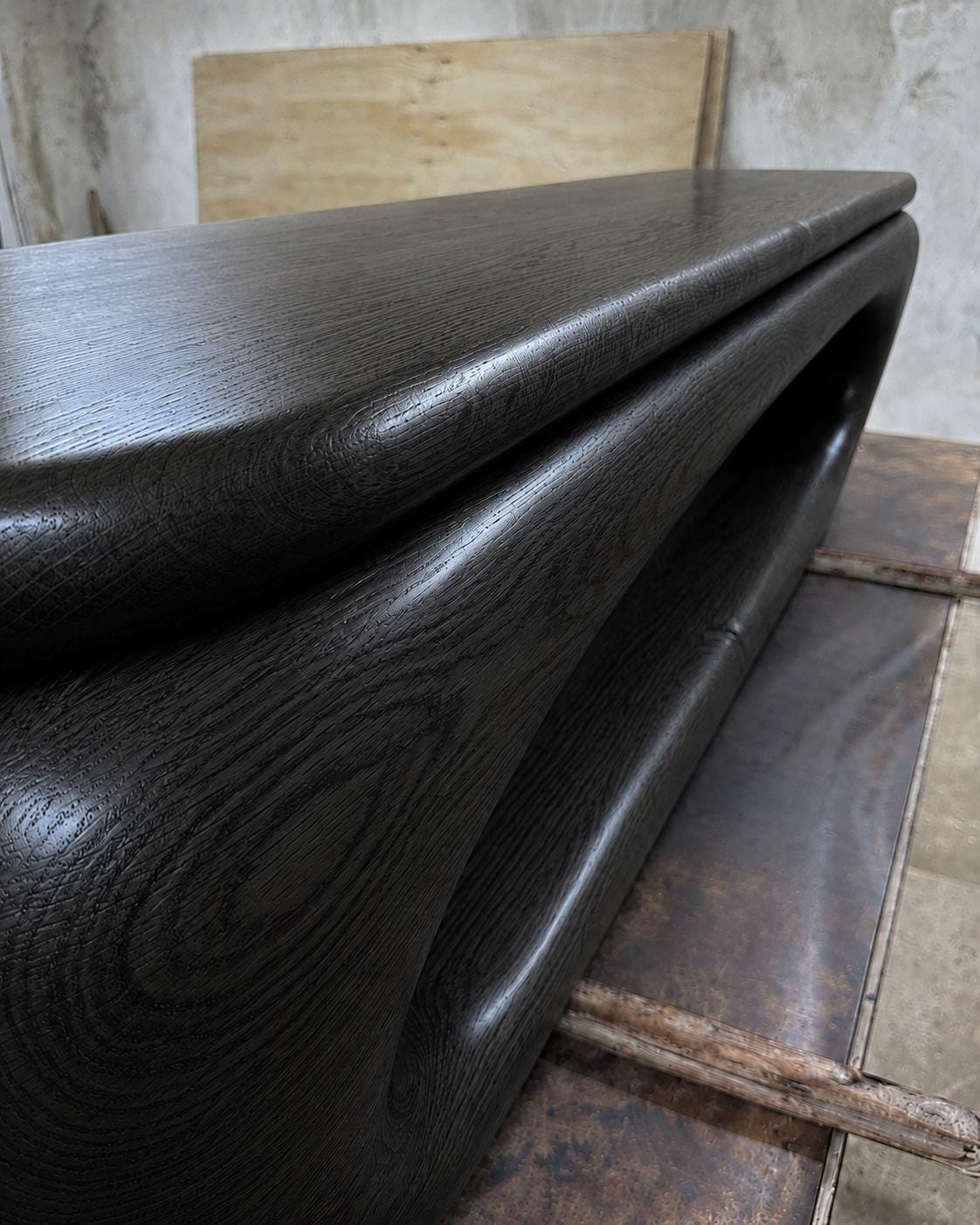 May include: A dark stained wooden table with a unique, curved design. The table has a smooth, glossy finish and a modern aesthetic. The wood grain is visible, adding texture to the piece. The table's dimensions are not visible in the image.