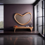 May include: A large, organic, kidney-shaped wall mirror with a thick, light-toned wooden frame. Below the mirror sits a matching, low-profile wooden bench with curved legs, holding a small orange bowl, a stack of books, and a dark gray vase.