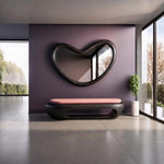 May include: A dark wood bench with a soft pink upholstered seat cushion positioned below a large, irregularly shaped, organic-form wall mirror with a dark wood frame, set against a solid dark purple wall in a bright, open interior space.